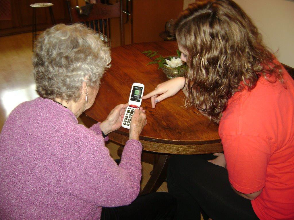 An AAH volunteer shows a member how to use features of a new cell phone.
